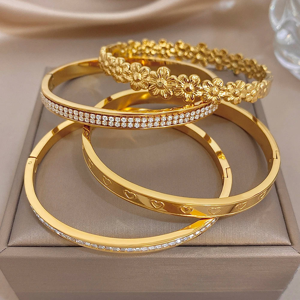 Gold tone bangle cuffs with rhinestone edges and raised floral heart motif