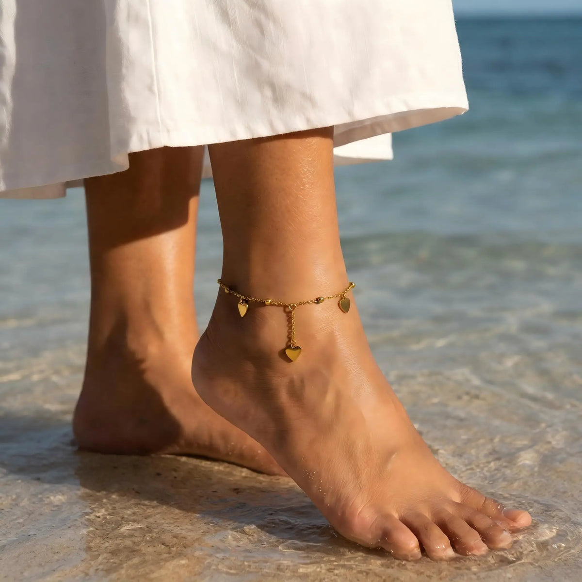 Gold-tone heart beaded adjustable anklet on bare foot with small heart charms