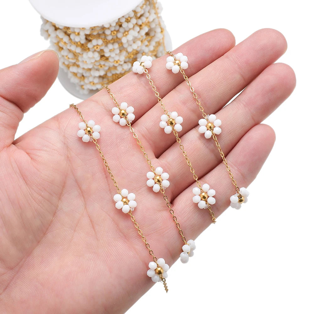 White daisy flower beaded chain with gold-tone links held in hand