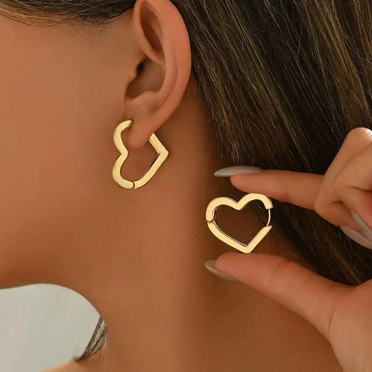 Gold heart-shaped hoop earrings on model ear