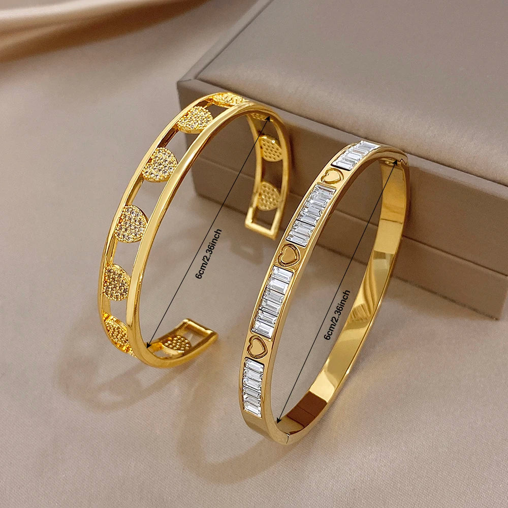 Gold and clear stone heart cuff bangles set on display, hinged open bracelets