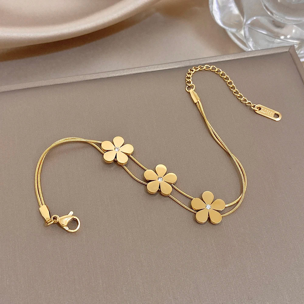 Gold double-layer snake chain bracelet with five flower charms and crystal centers, lobster clasp