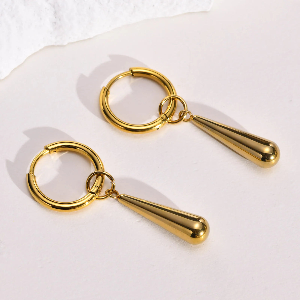Close view of gold-tone hoop earrings and elongated teardrop pendants