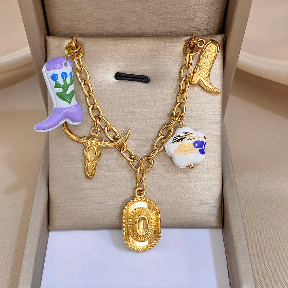 Gold chain necklace with purple flower, blue-and-white bead, and oval pendant