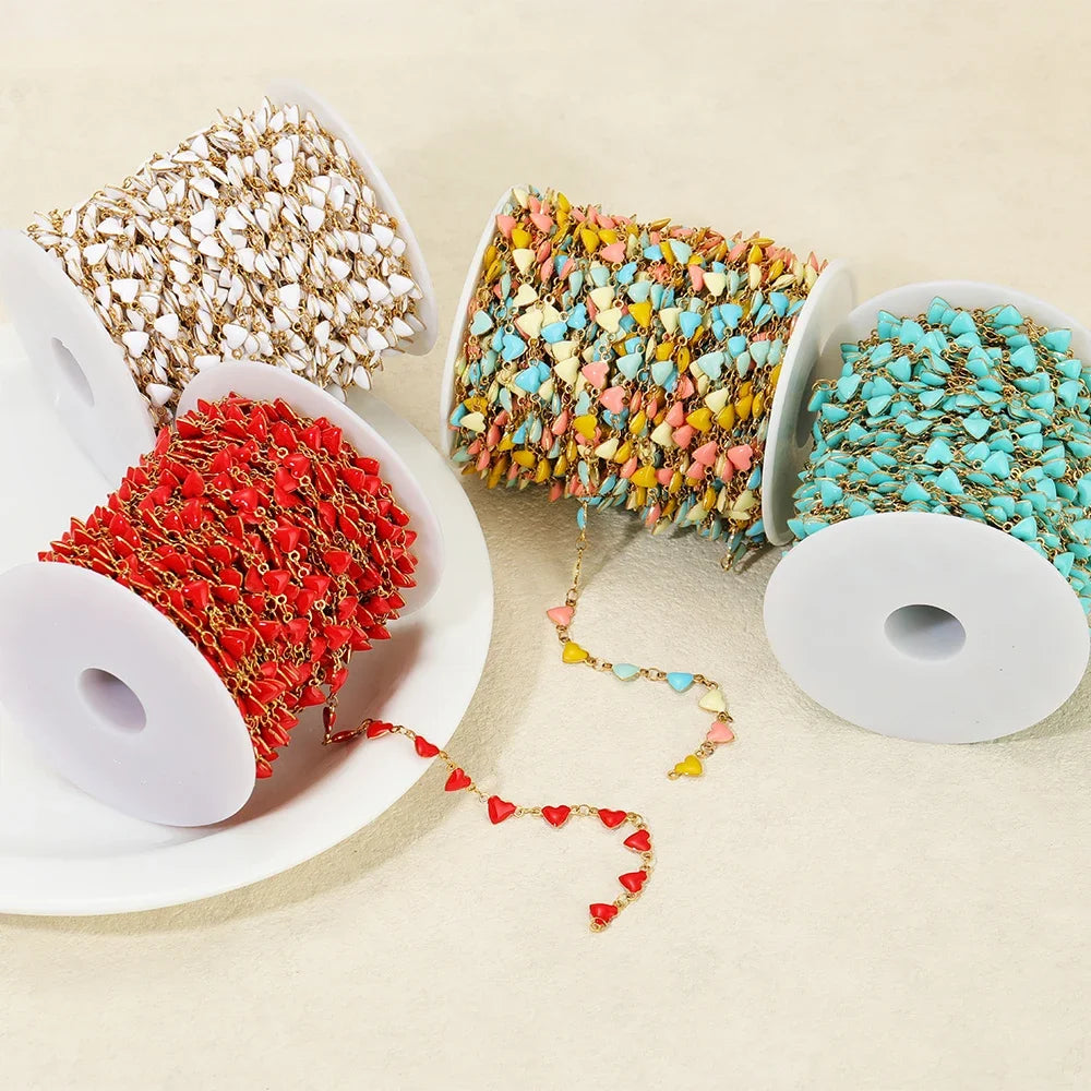 Enamel heart charm chains on spools with red, multicolor, and white-gold tones