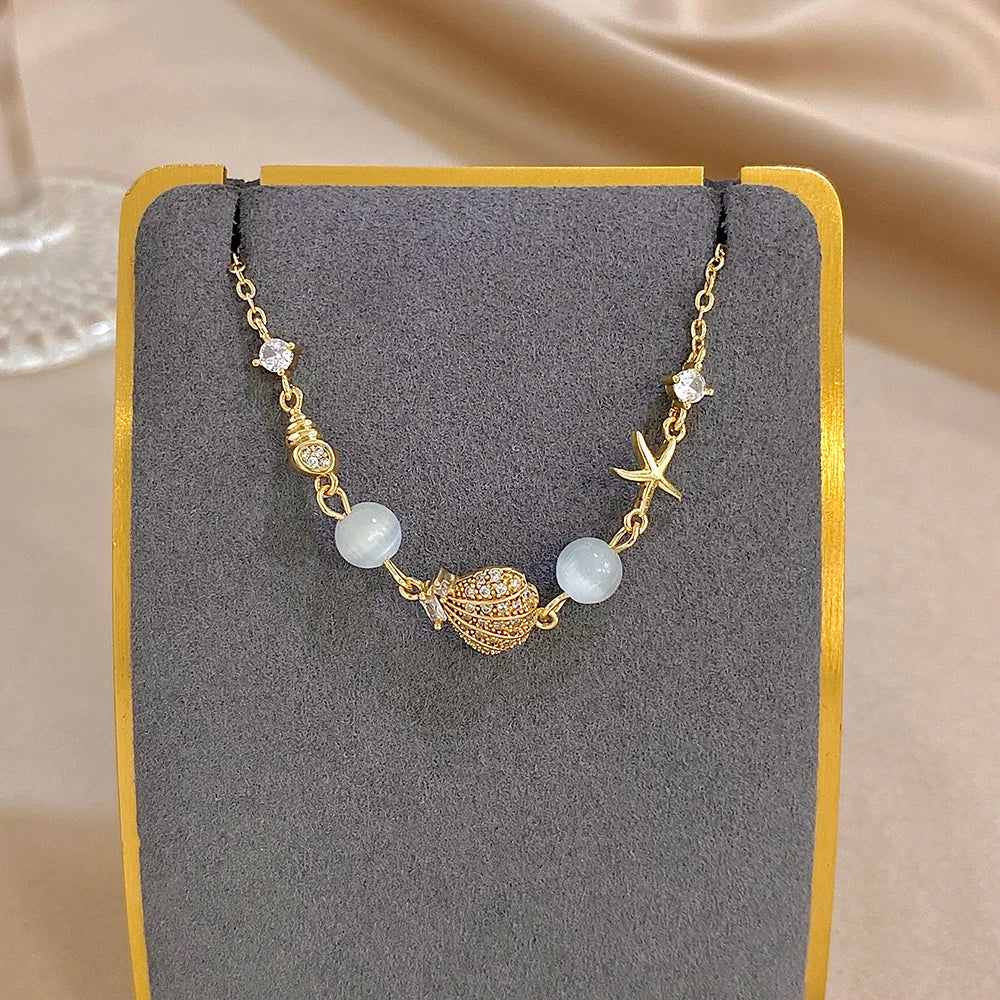 Gold-tone shell-and-star charm bracelet with moonstone-style beads and rhinestone stones