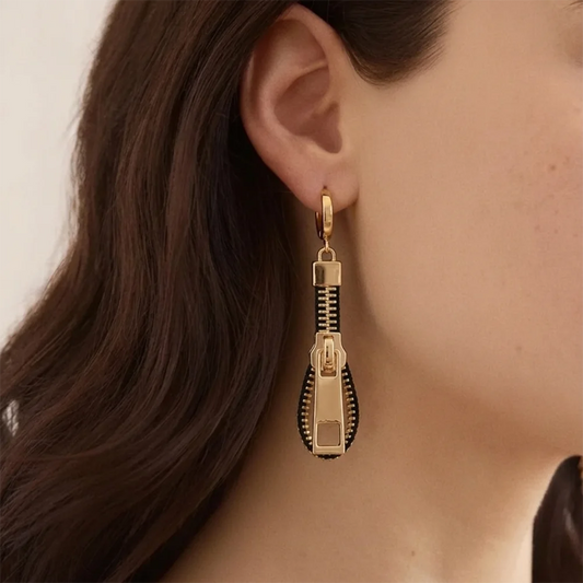 Gold-tone zipper drop earrings with black stripe and rectangular charm, worn on ear