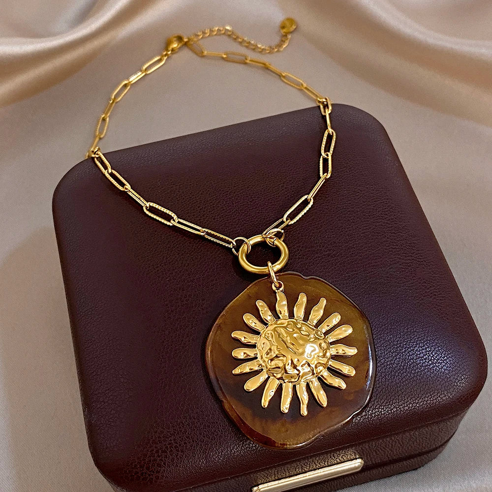 Gold-tone chain pendant necklace with amber round sun charm and gold sunburst relief
