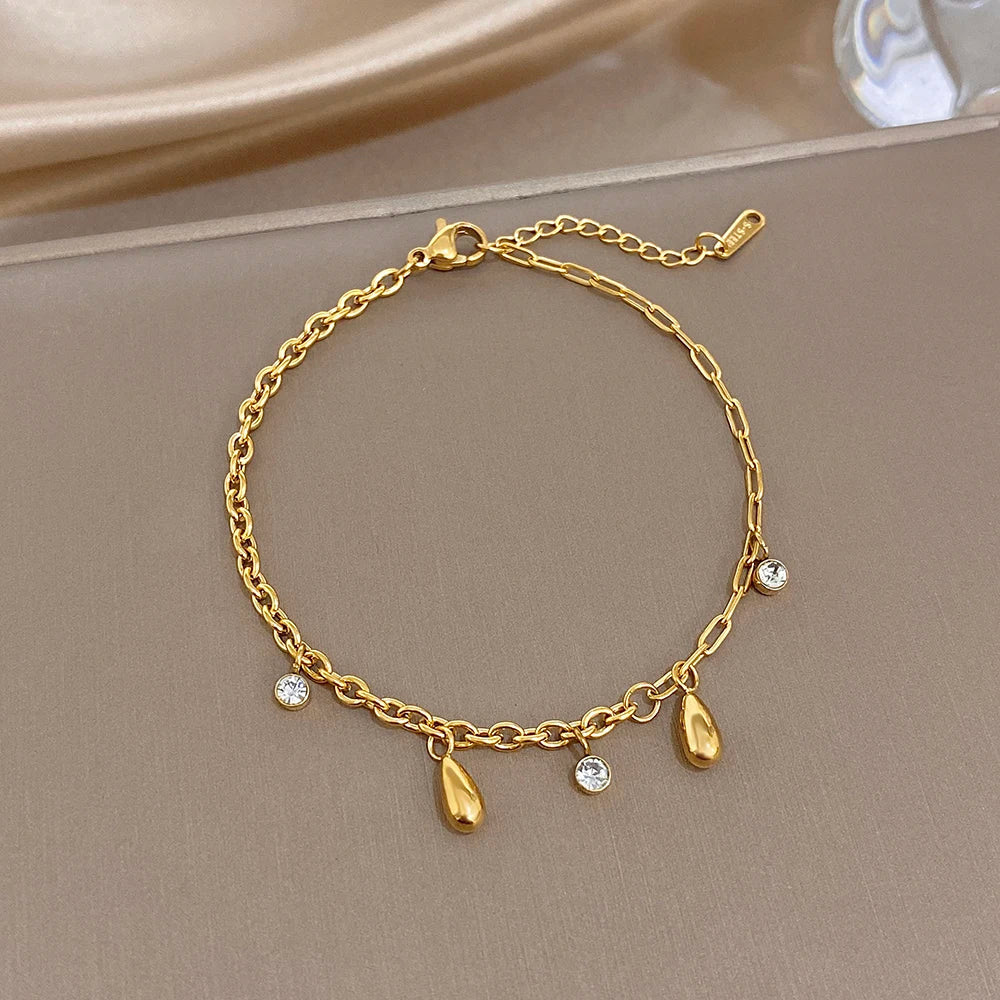 Gold-tone slim chain bracelet with crystal drops and small flower charms