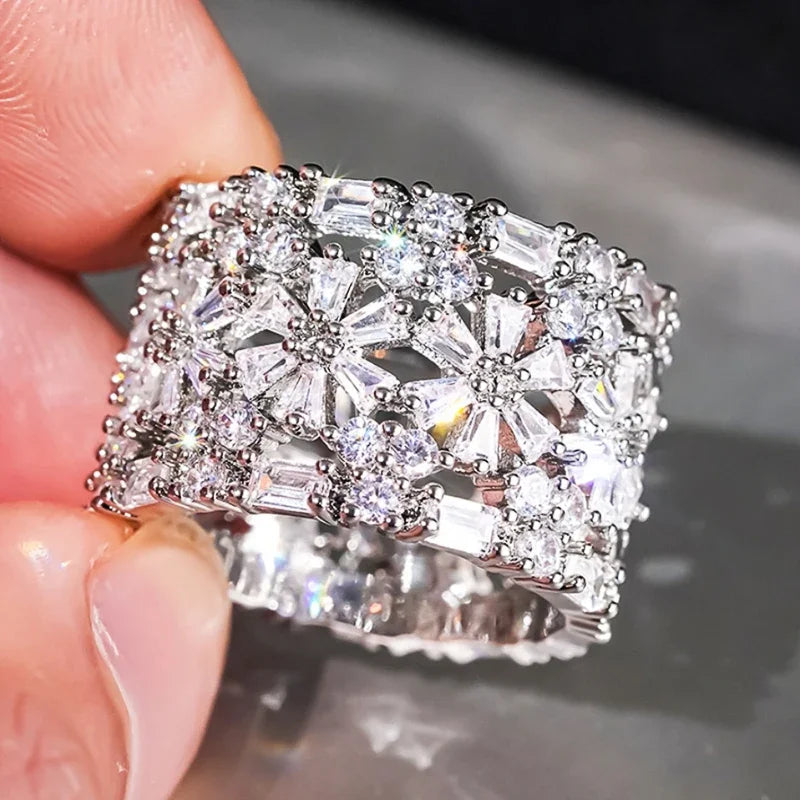 Clear CZ halo ring with glittering silver-toned setting held on fingertips