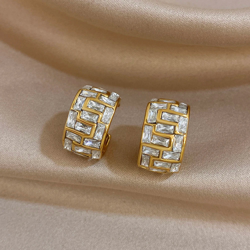 Gold-tone geometric hoop earrings with a maze-like pattern and clear stones