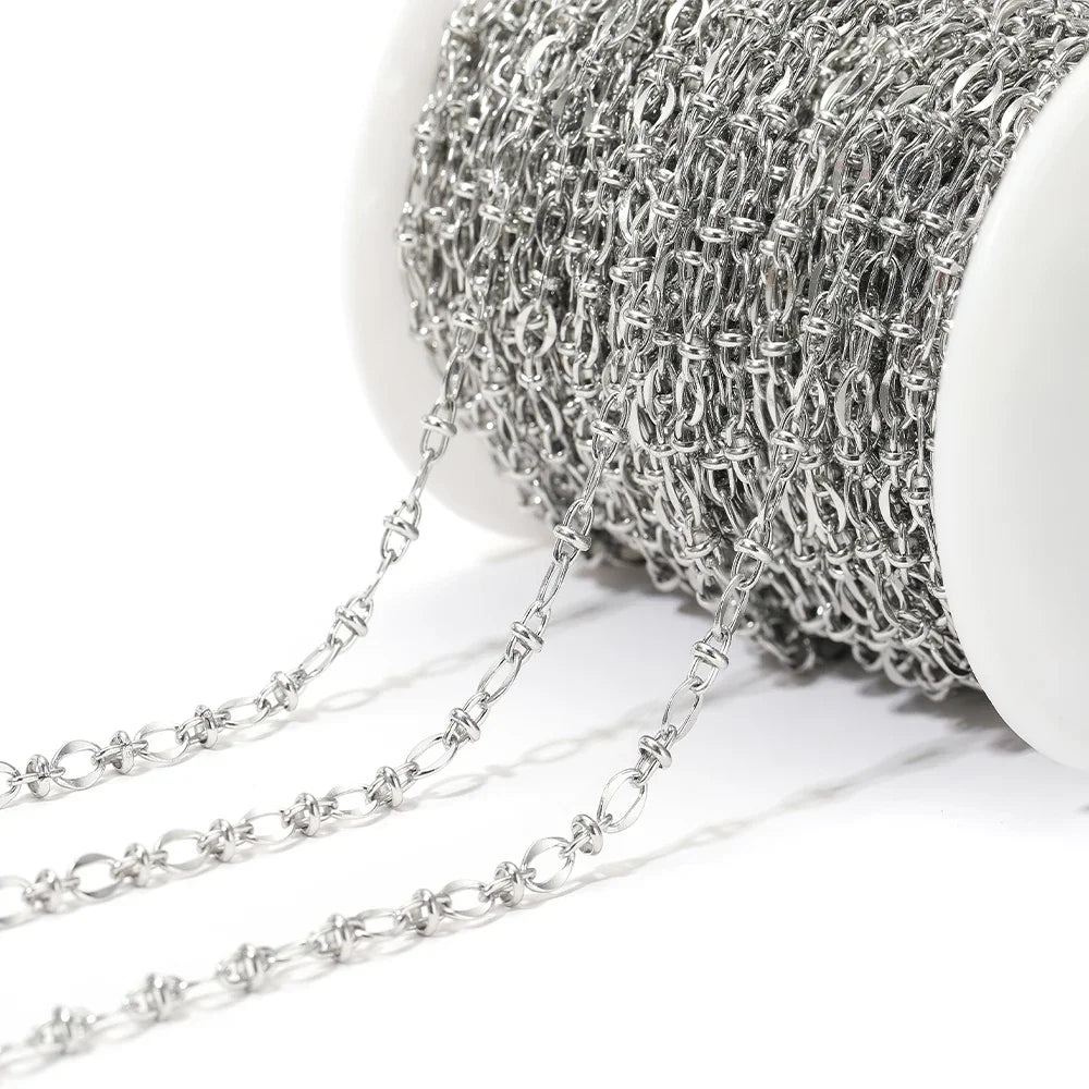 Close-up silver oval link chain strand draping from a white spool