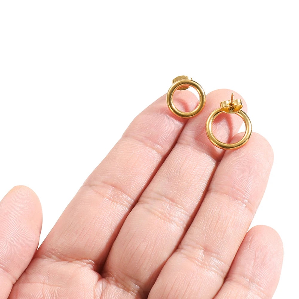 Gold round hollow stud earrings close-up on fingers, circular hoops and back posts