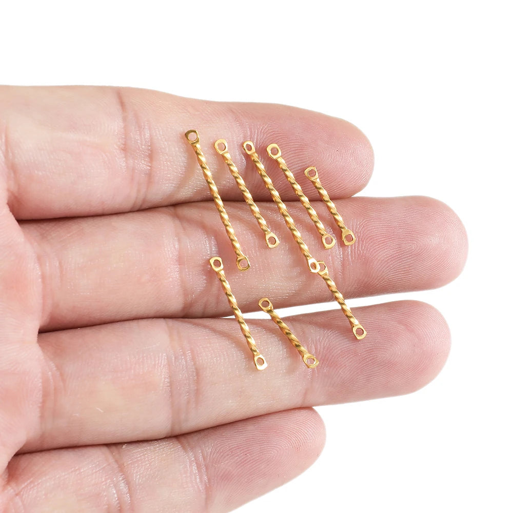 Gold twisted rod double-hole connectors held in hand, thin link bars