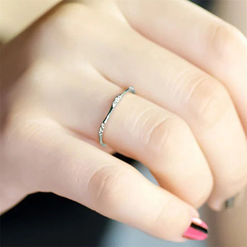 Minimalist cubic zirconia wedding ring with slim silver band on a woman's finger