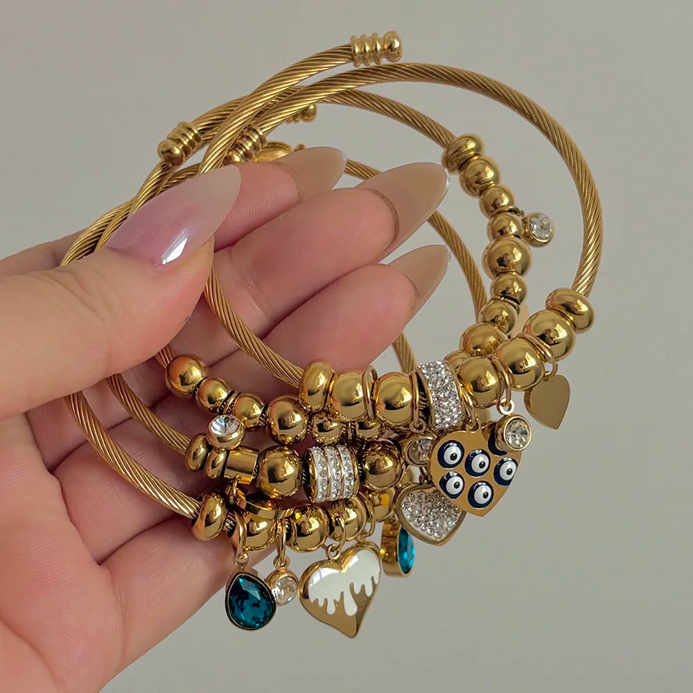 Gold-tone beaded charm bracelet with heart, owl, blue drop, and crystal accents