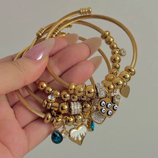 Gold-tone beaded charm bracelet with heart, owl, blue drop, and crystal accents