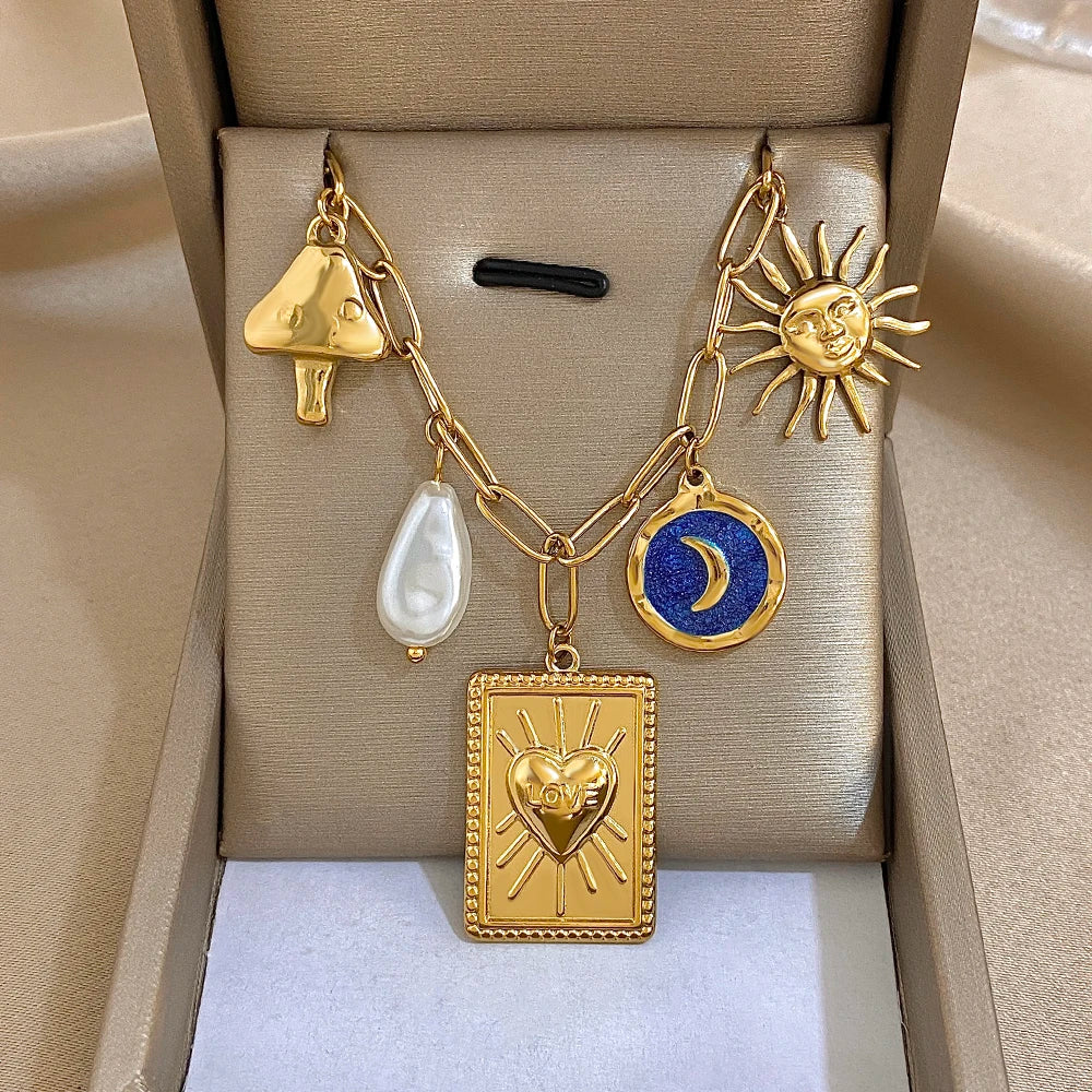 Gold chain necklace with heart pendant, blue circular charm, and teardrop charm