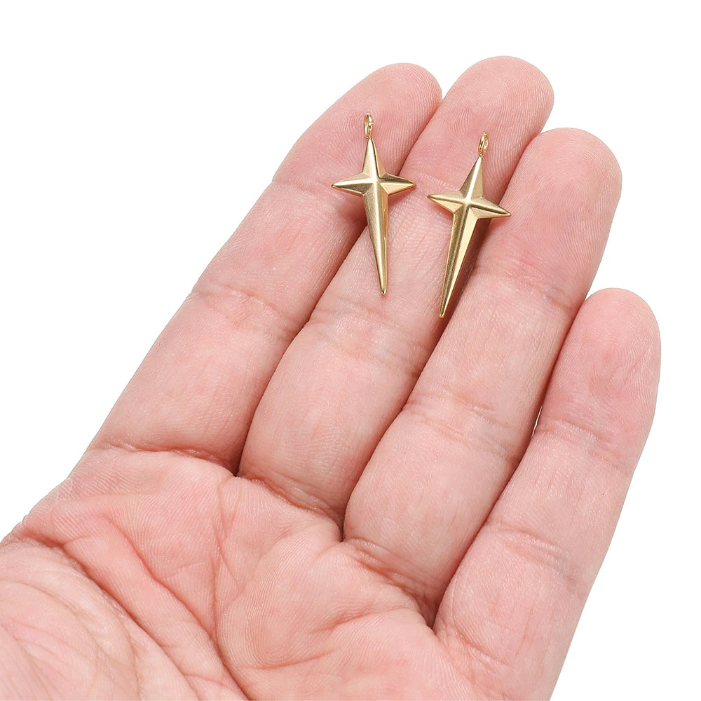Gold-tone star cross charms with hanging loops, stainless steel, held in hand
