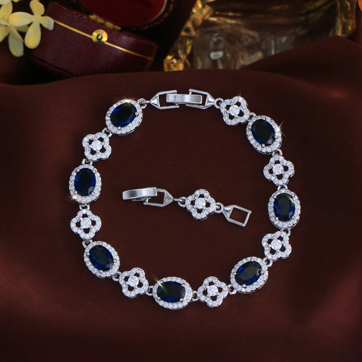 Silver-tone tennis bracelet with dark blue oval stones and crystal flower links