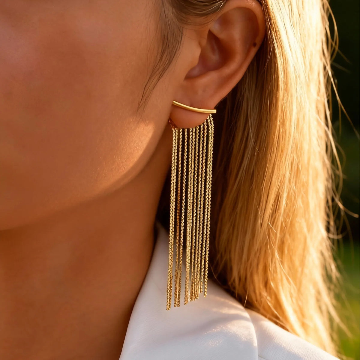 Gold long chain fringe tassel earrings worn on a model's ear