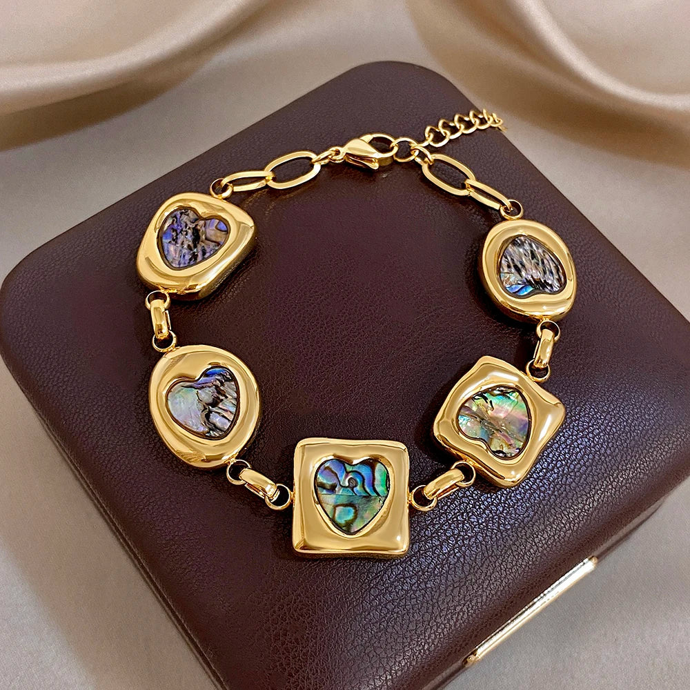 Gold-tone geometric charm bracelet with iridescent abalone-shell heart and square beads