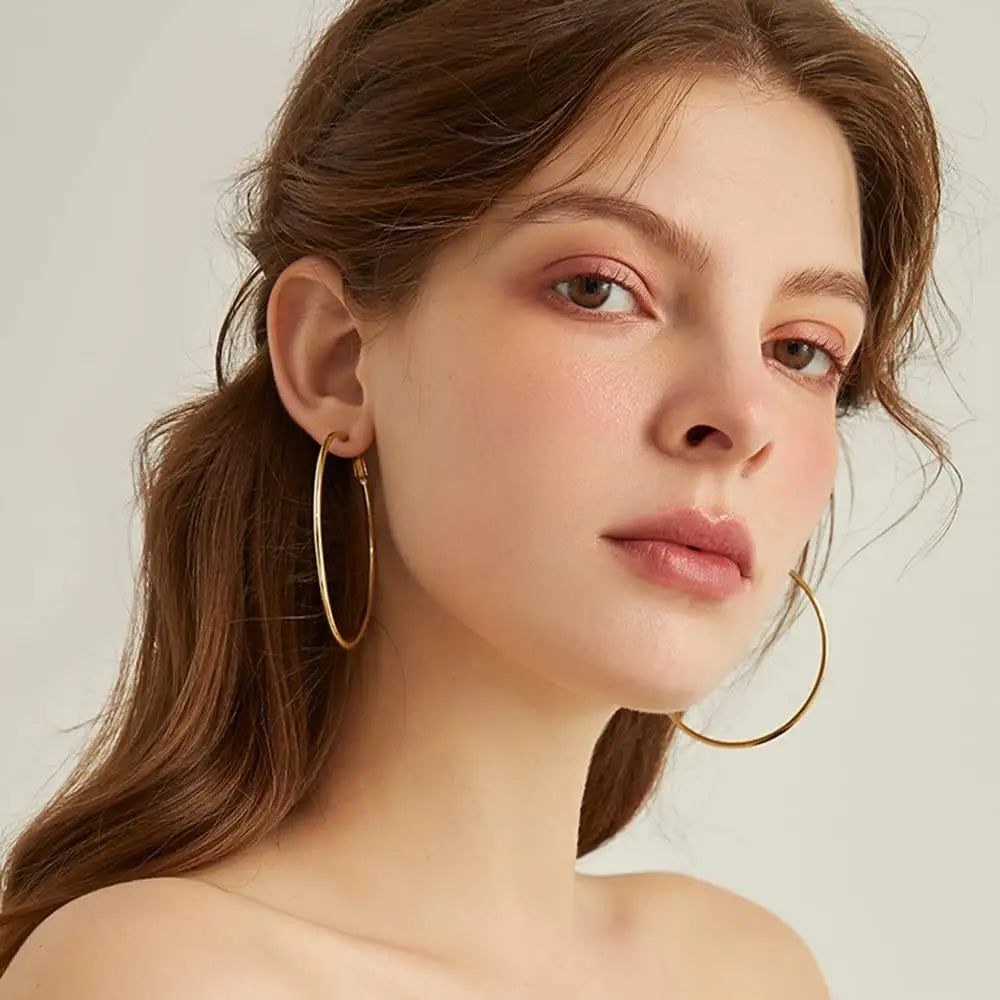 Large gold-tone hoop earrings worn by a model.