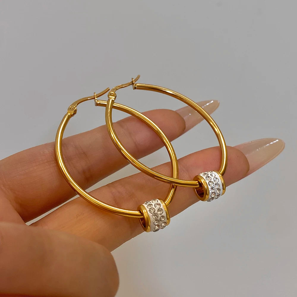 Gold-plated hoop earrings held in hand, clear rhinestone bead bands on front