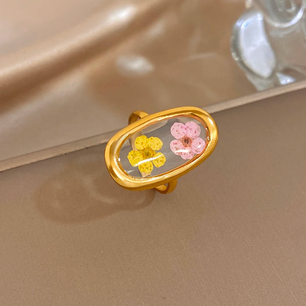 Gold-tone open oval ring with pink and yellow flowers in a clear window