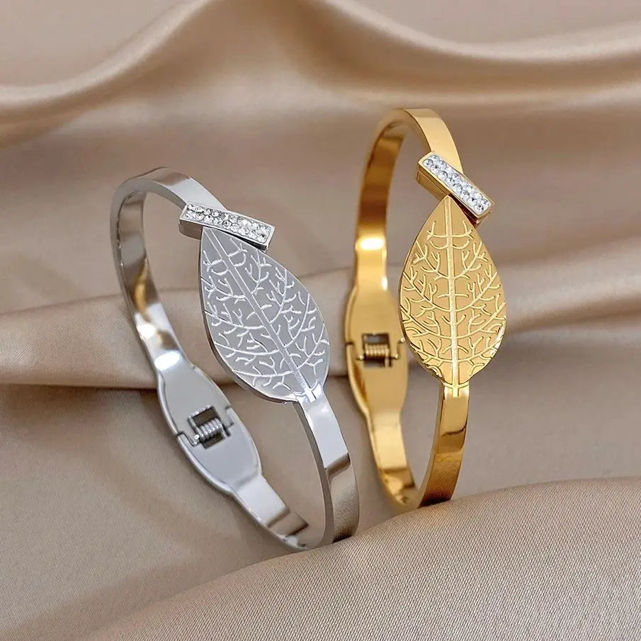 Gold leaf-pattern cuff bangle with rhinestone square detail and hinged clasp.