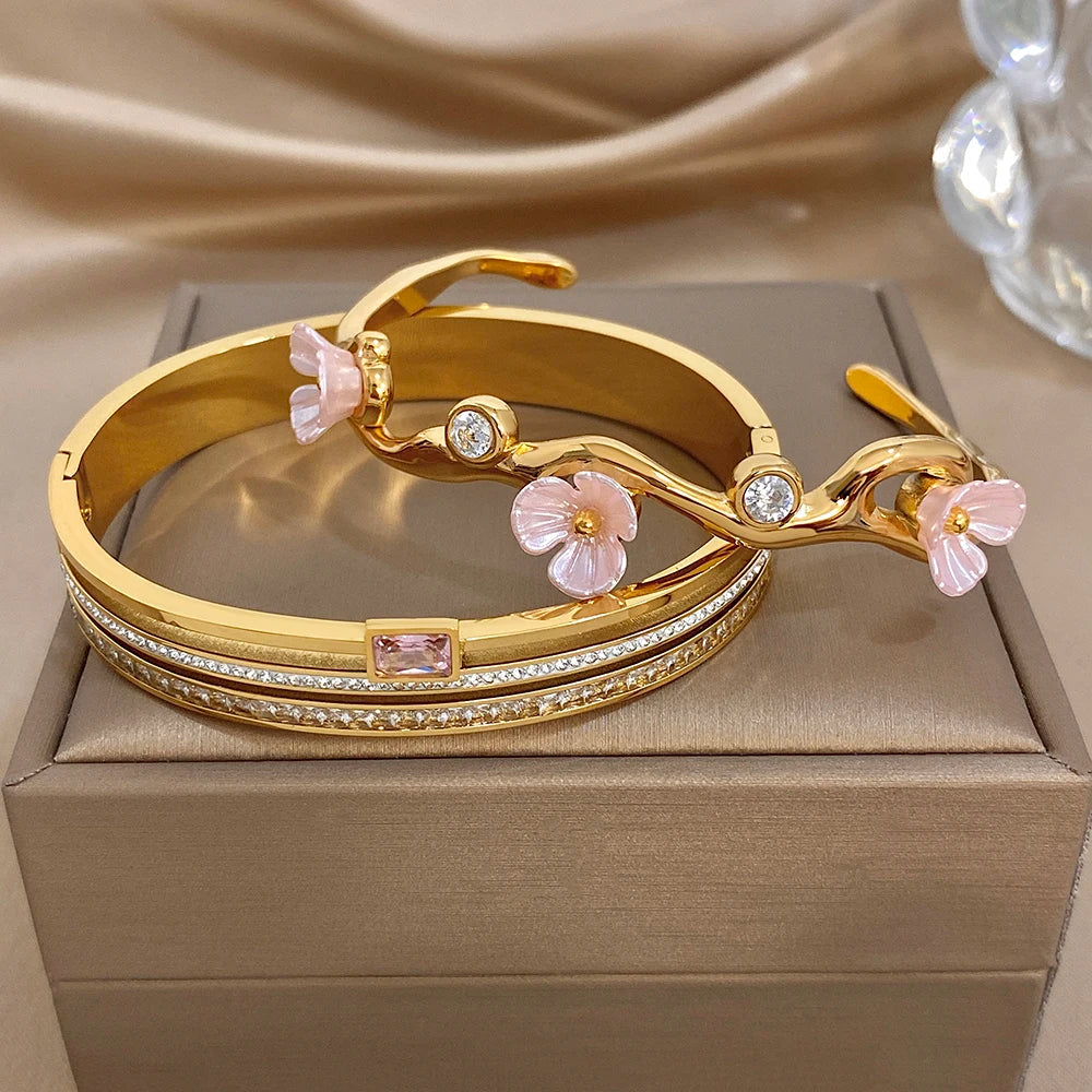 Gold-plated pair of cuff bangles with pink floral accents and clear rhinestone trim