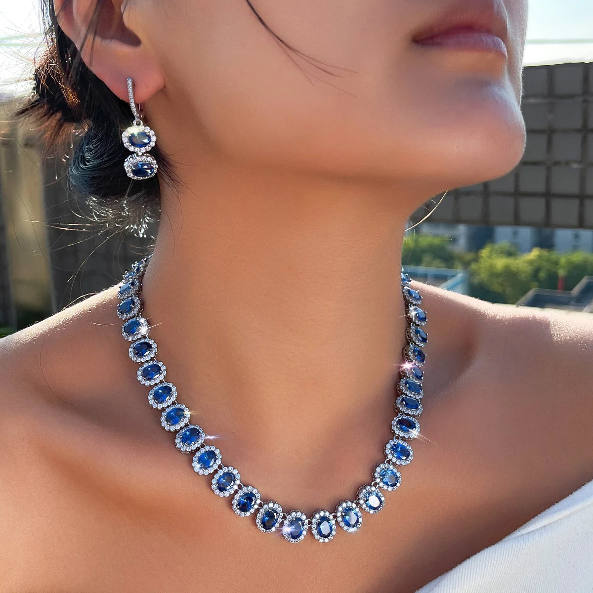 Royal blue cubic zirconia jewelry set with drop hoop earrings and matching necklace on model