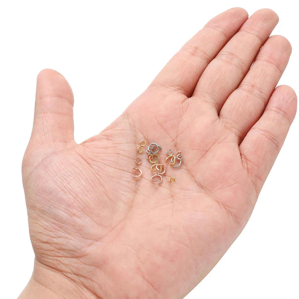 Hand holding assorted split jump rings in rose gold, gold, and silver