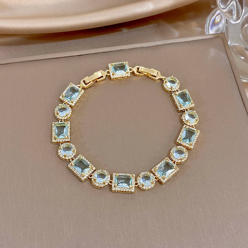 Gold-tone geometric link bracelet with blue square and round crystal stones, open-work links