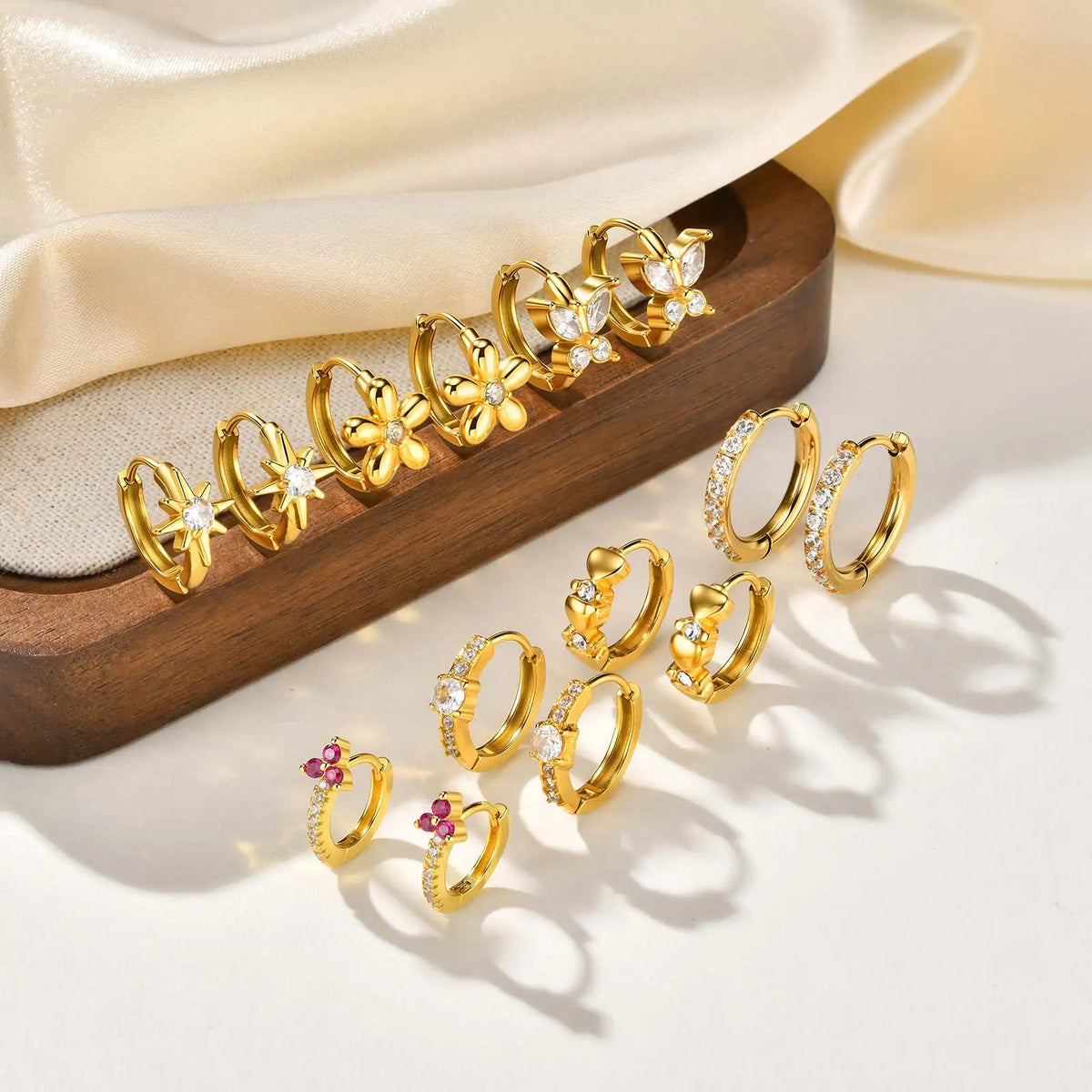 Gold-tone huggie hoop earrings with clear cubic zirconia flower accents