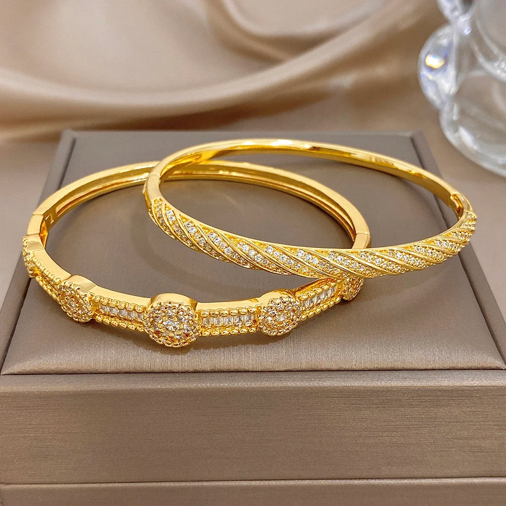 Gold-tone hinged crystal bangles set on a gift box, stacked side view