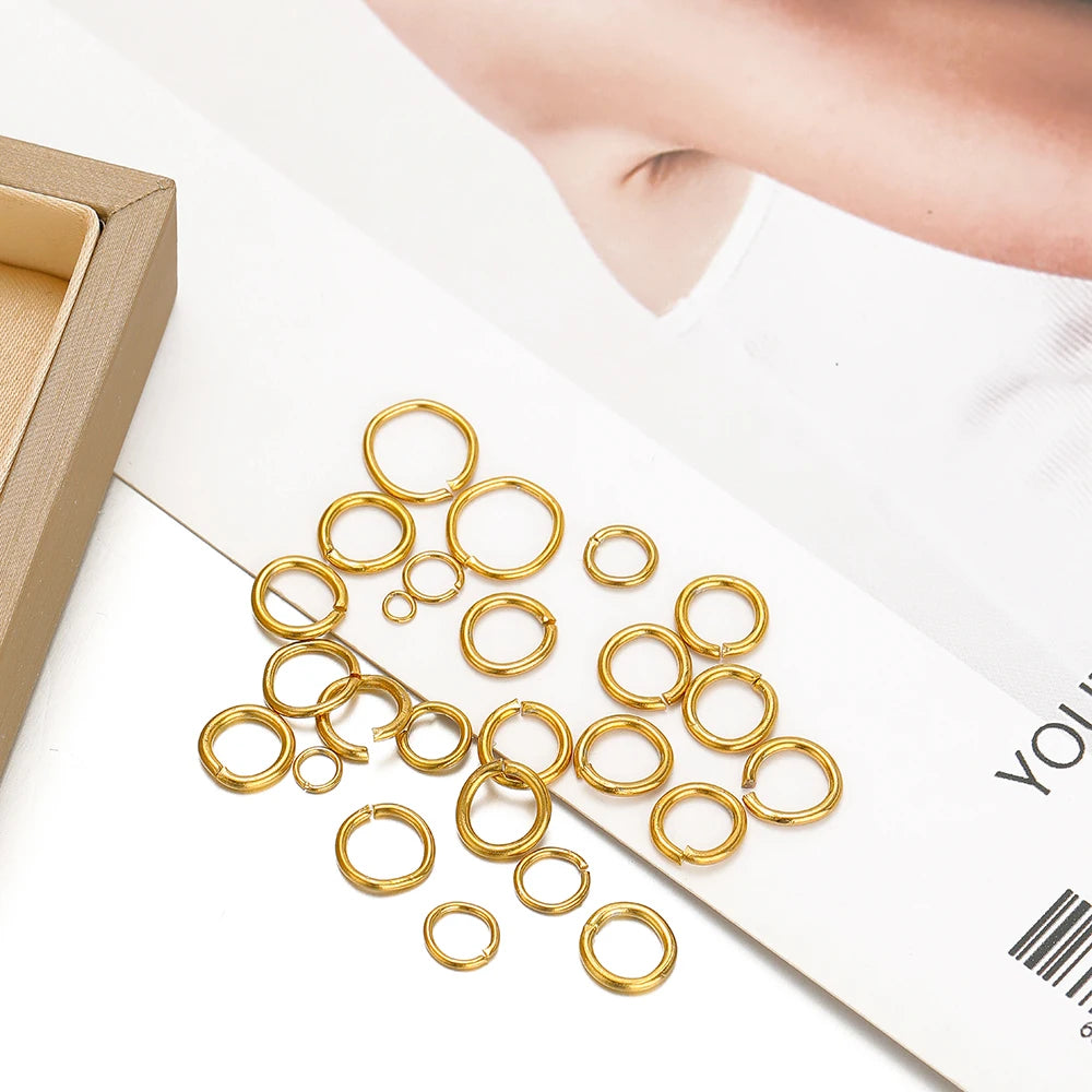 Gold-colored jump rings in a loose pile on a flat card near a hand