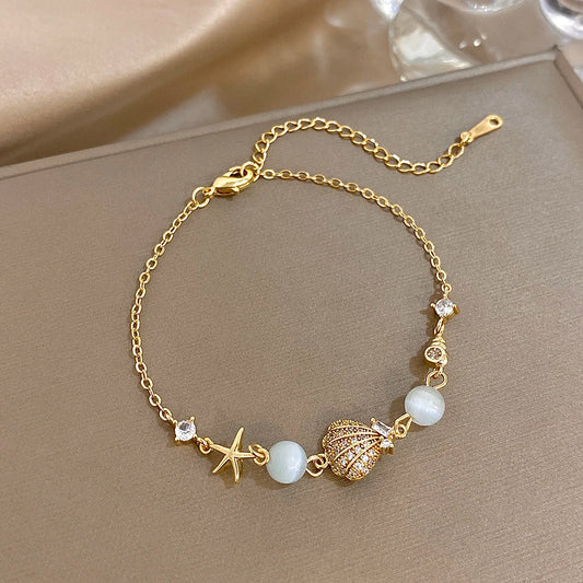 Gold-tone beaded bracelet with starfish, shell, moonstone-style beads and rhinestone accents