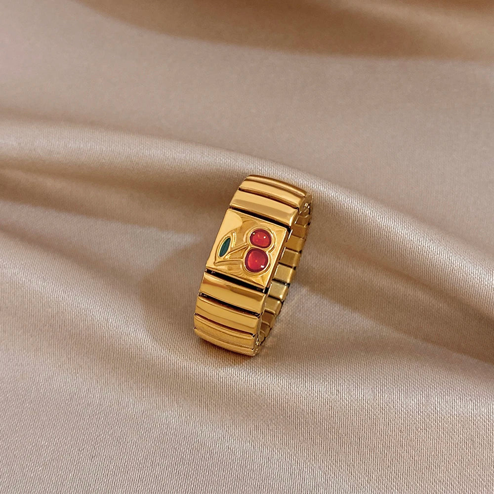 Gold adjustable watchband-style finger ring with red cherry enamel and green leaf accents
