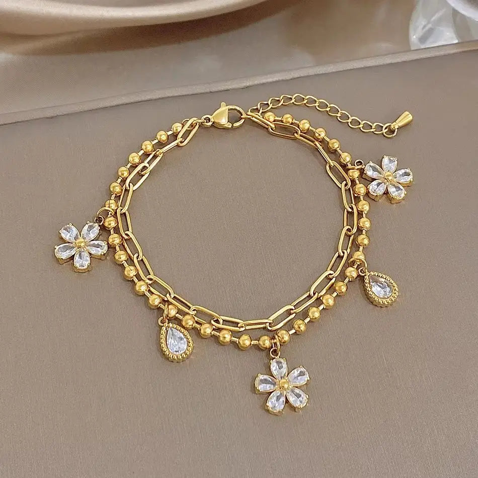 Gold-plated chain bracelet with dangling crystal flower and teardrop charms
