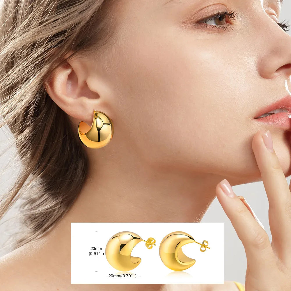 Gold crescent-shaped hoop earrings worn on the ear