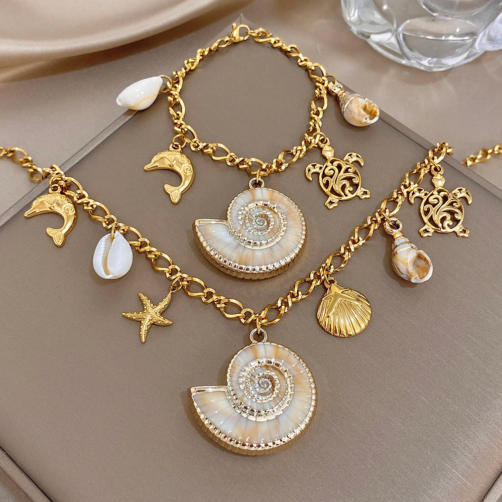 Gold-tone charm necklace and bracelet set with dolphin, starfish, and shell pendants
