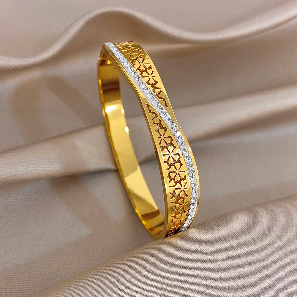 Gold cuff bangle with engraved floral border and clear stone edge detail