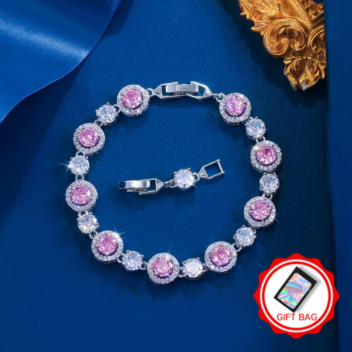 Silver-tone tennis bracelet with round pink stones, clear accents, and a gift bag