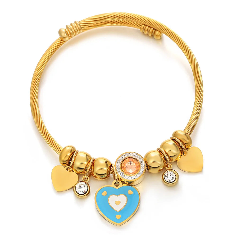 Gold-tone beaded bracelet with round crystal center, heart charm, and blue enamel heart