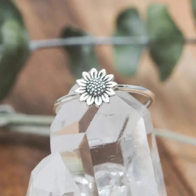 Silver sunflower finger ring on a clear faceted crystal display
