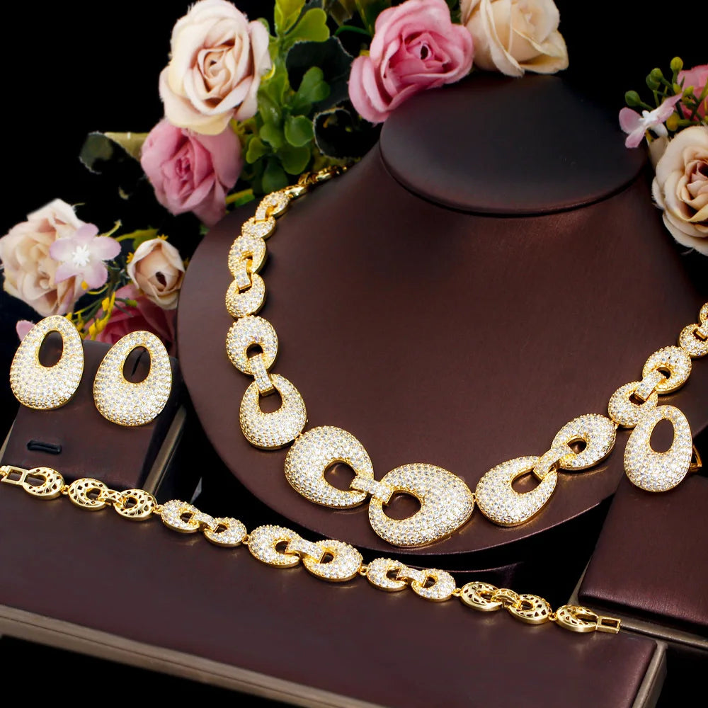 Gold-tone zirconia jewelry set on stand: necklace, bracelet, and hoop earrings