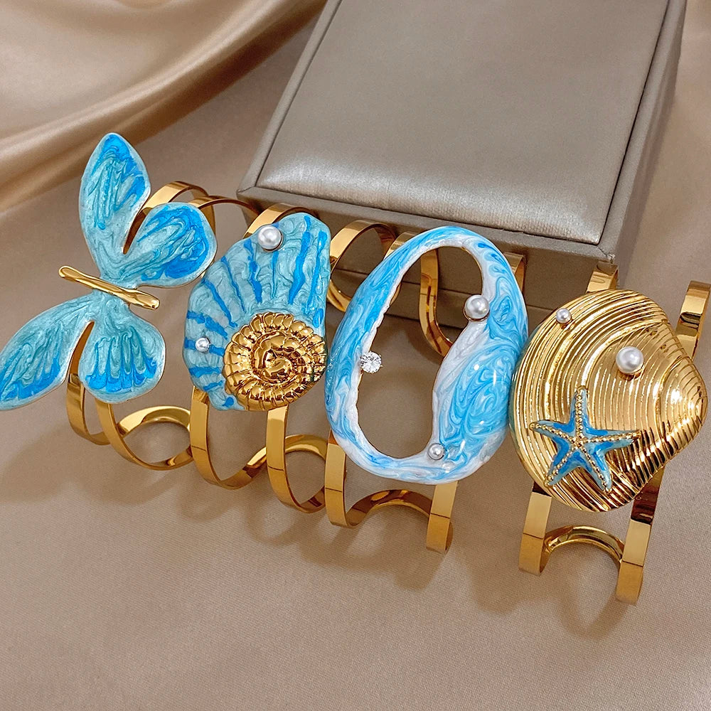 Gold-plated wide cuff bracelet with blue enamel butterfly and starfish accents