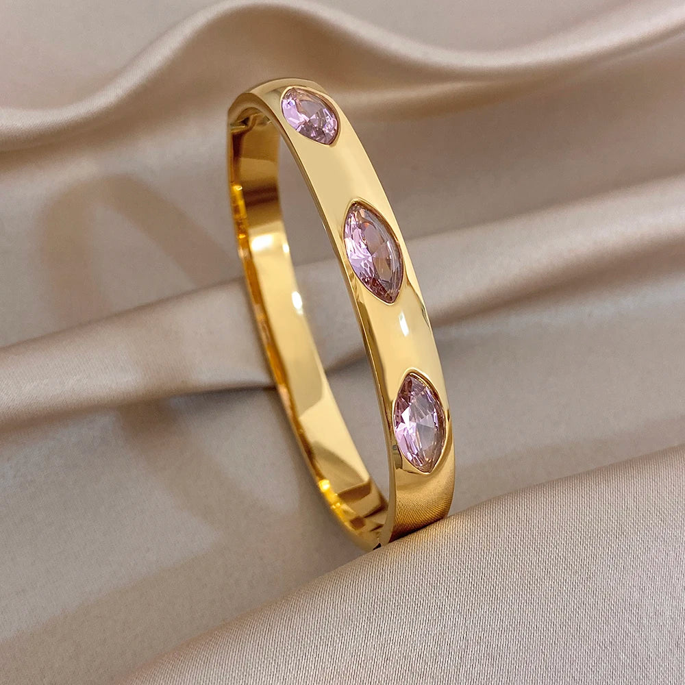 Gold tone slim bangle with pink zircon oval stones, smooth curved cuff