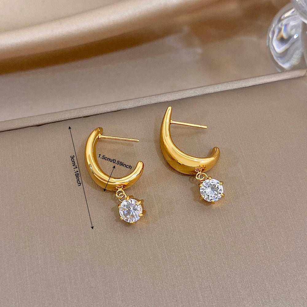 Gold-tone hoop earrings with clear round crystal dangles, shown on display